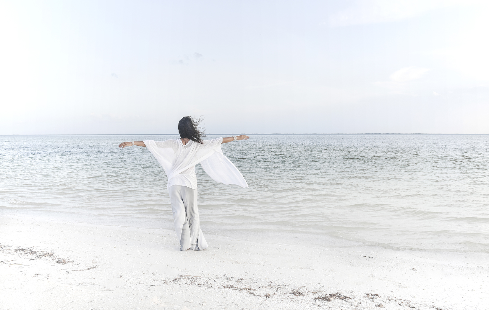 Isabella standing with open arms beside the ocean